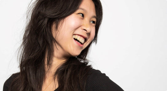 Smiling woman with long dark hair looking to the side.