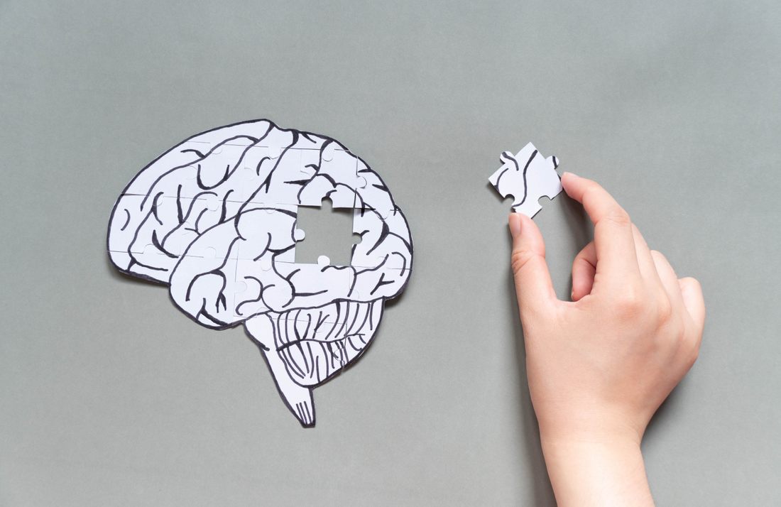 Puzzle piece completing brain shape on gray background.