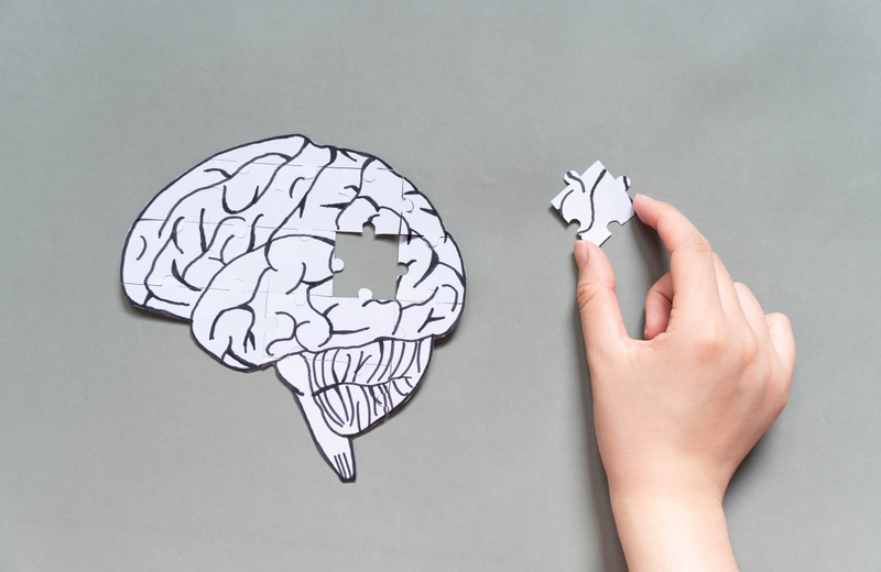 Puzzle piece completing brain shape on gray background.