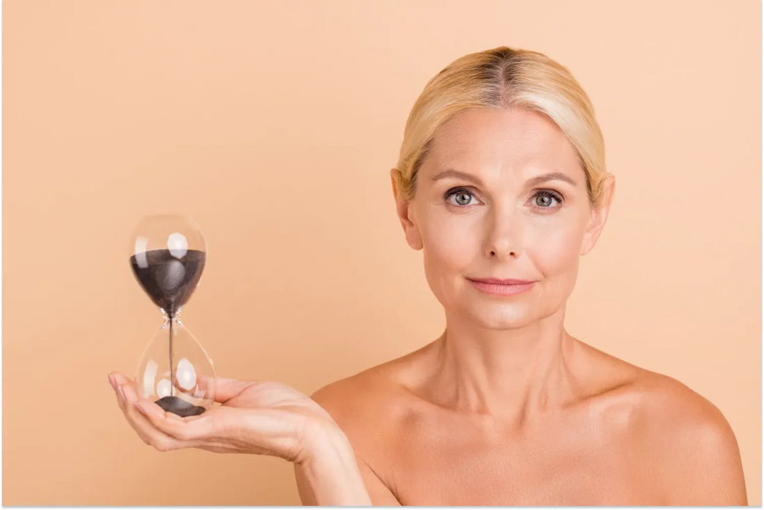 Older woman holding an hourglass, symbolizing time and aging.
