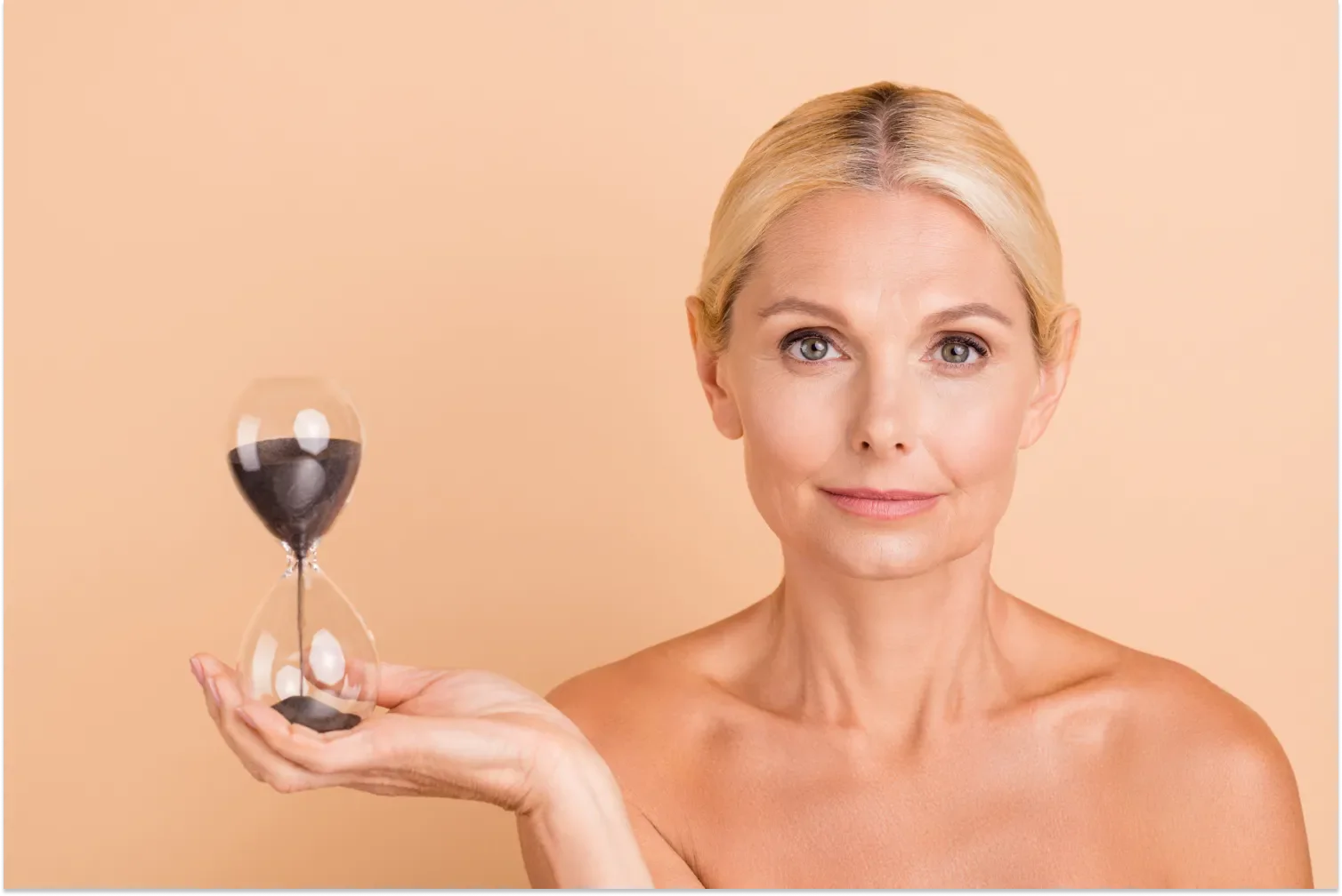 Older woman holding an hourglass, symbolizing time and aging.