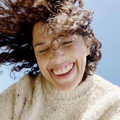 Smiling woman with curly hair enjoying a sunny day.