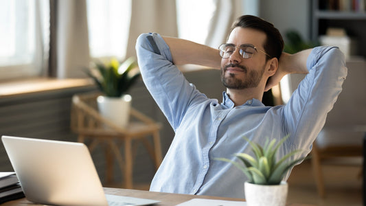 Man relaxing at desk with laptop, feeling peaceful.