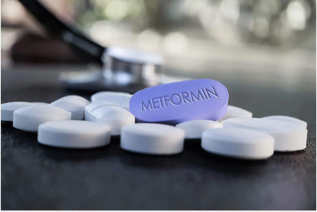 Purple Metformin pill among white tablets on table.