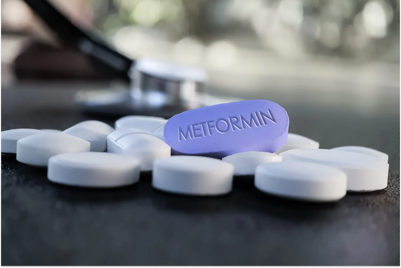 Purple Metformin pill among white tablets on table.