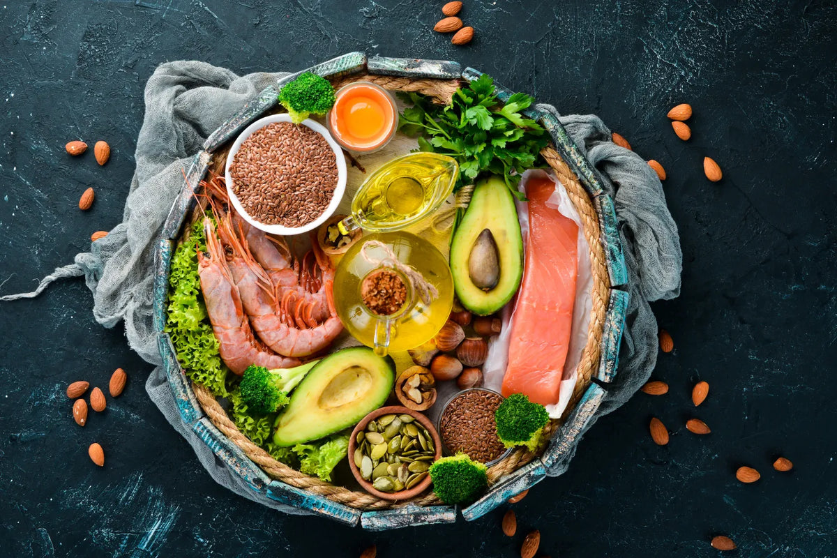 Assorted healthy foods with salmon, avocado, and nuts on a dark background.