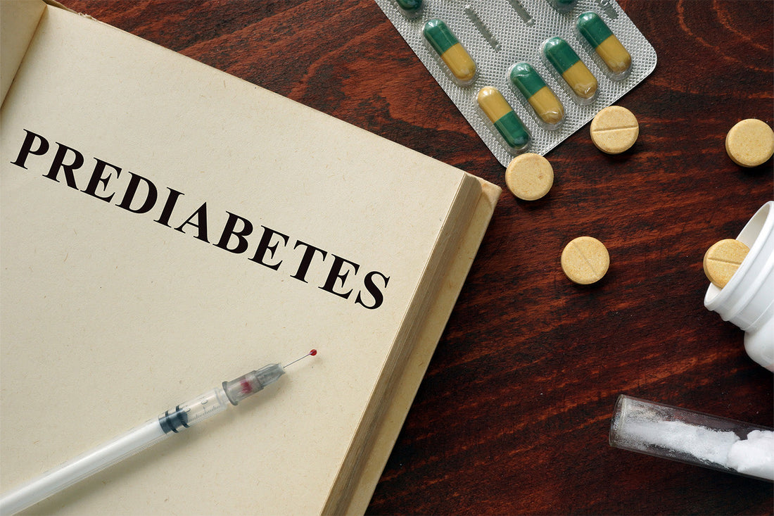 Open book with Prediabetes text, syringe, and pills on a wooden table.