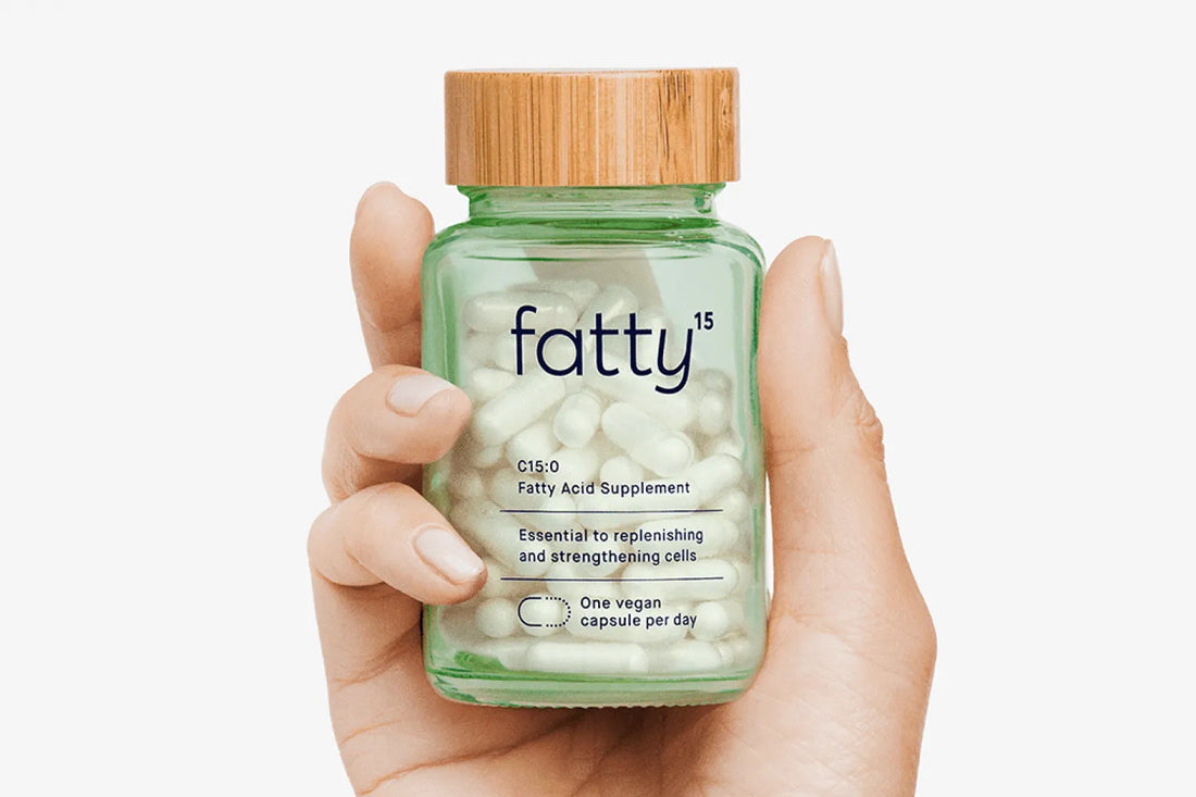 Hand holding a fatty15 C15 supplement bottle.