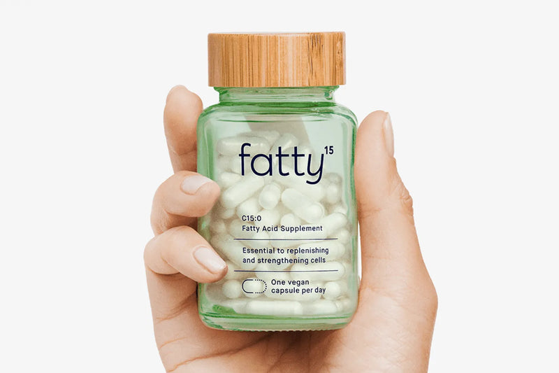 Hand holding a fatty15 C15 supplement bottle.