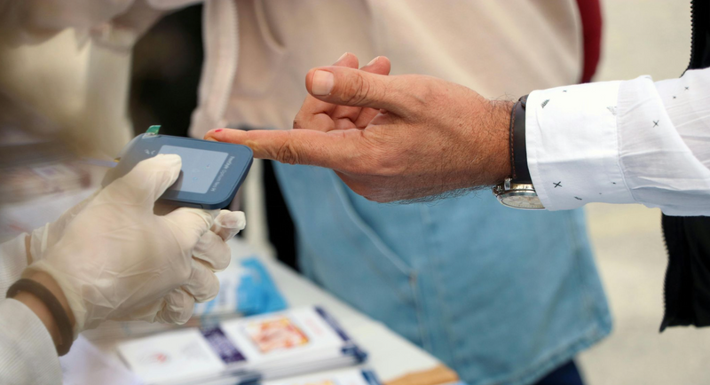 A close-up shot of a person’s finger being tested for blood glucose levels.