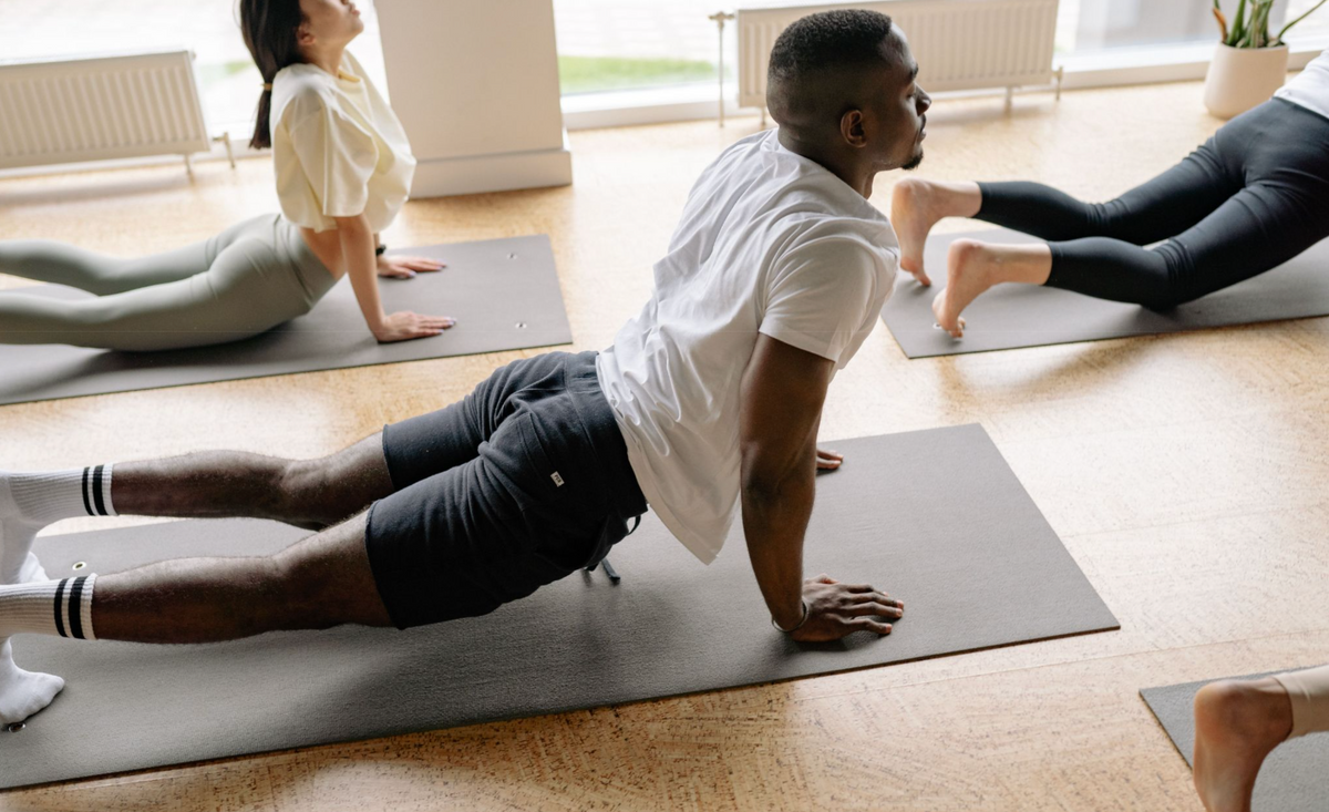 People are doing yoga in a studio, all on black mats.