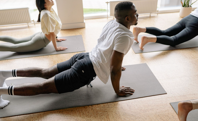 People are doing yoga in a studio, all on black mats.