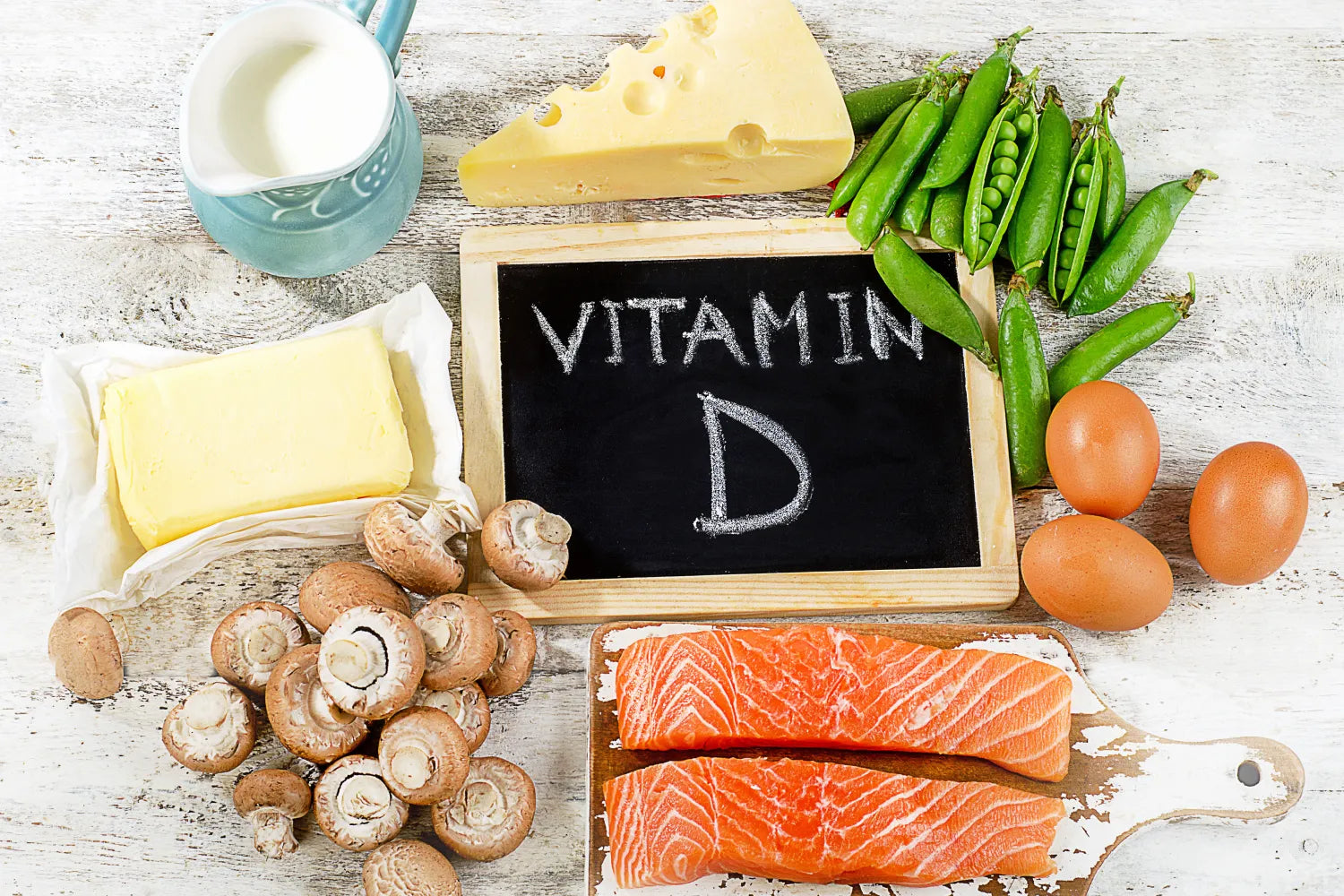 Vitamin D rich foods including salmon, eggs, cheese, and mushrooms on a table.