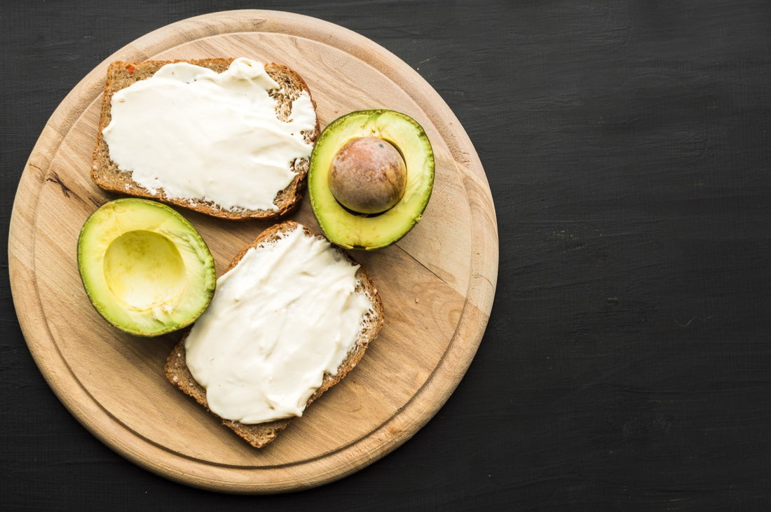 Avocado and cream cheese toast on a wooden board.