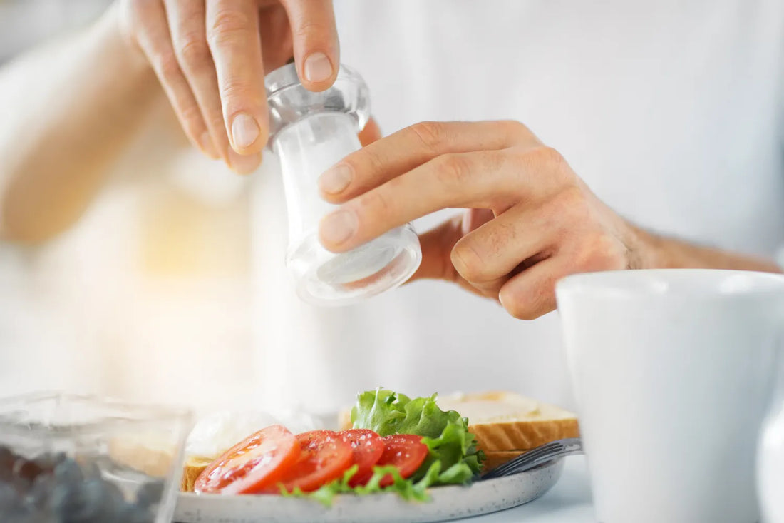 Adding salt to a salad with tomatoes and lettuce.
