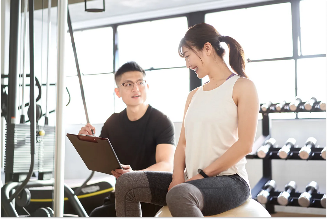 Personal trainer and client discussing workout plan in a gym.