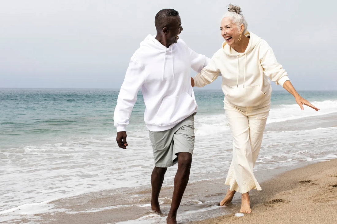 Older couple joyfully walking by the sea in casual clothing.