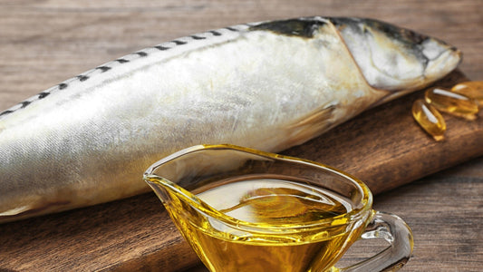 Whole mackerel and fish oil capsules on wooden board.