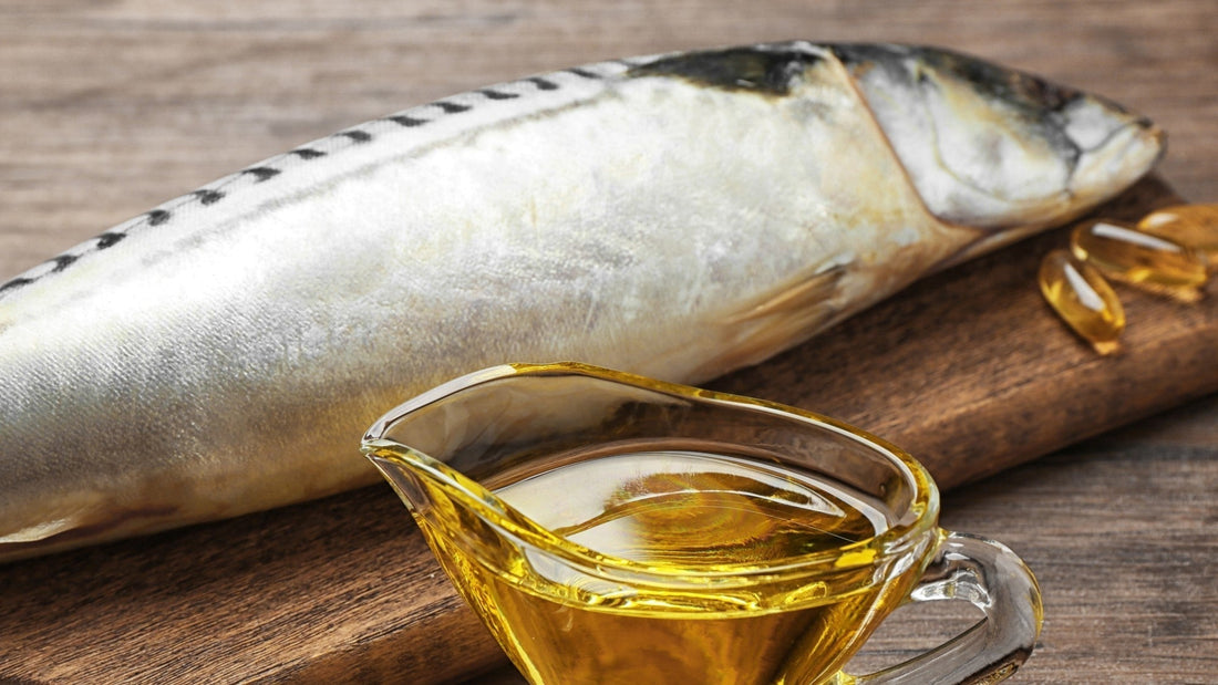 Whole mackerel and fish oil capsules on wooden board.