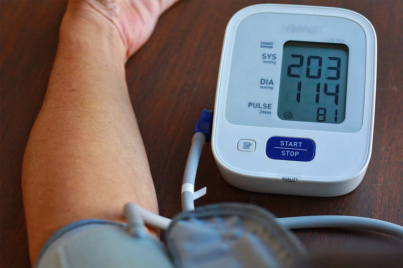 Digital blood pressure monitor displaying high reading.