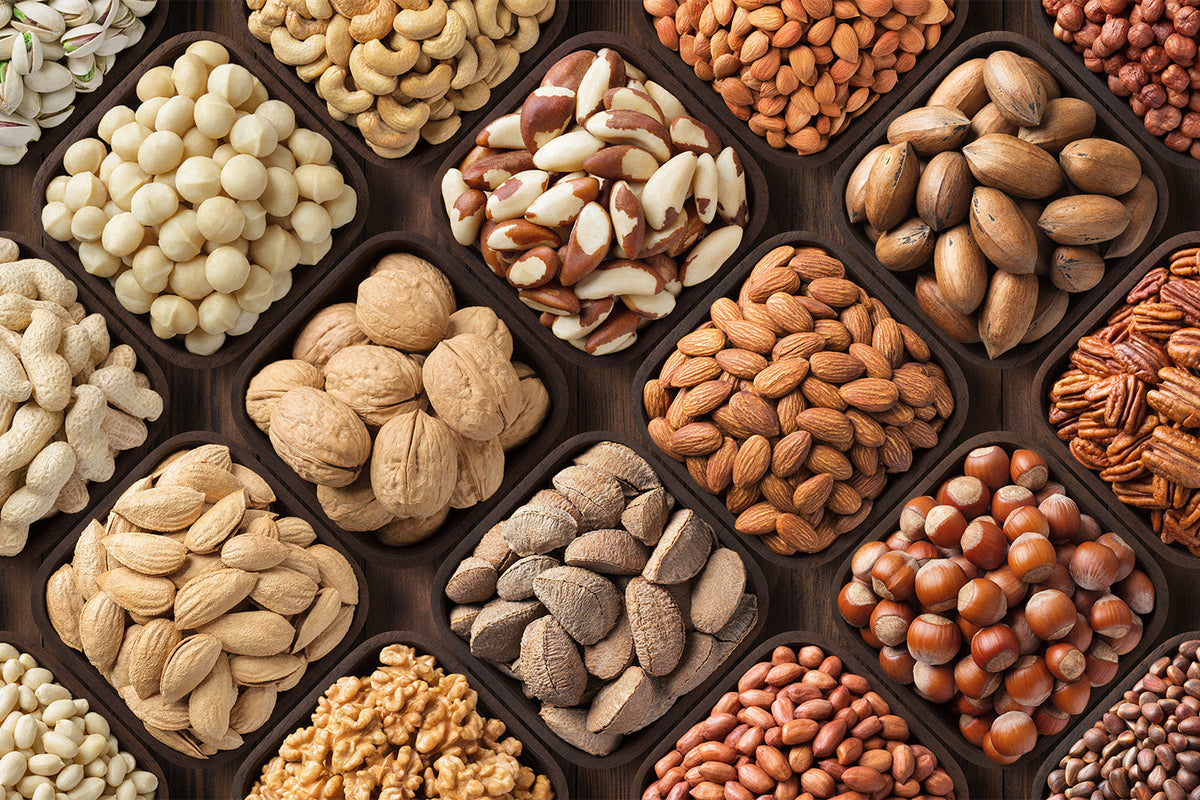 Assorted nuts in square bowls, including almonds, walnuts, and cashews.