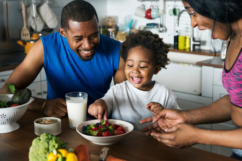 Family enjoying healthy breakfast with fruits and milk in kitchen.