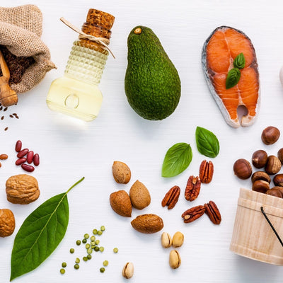 Healthy fats and protein sources: avocado, nuts, seeds, salmon, eggs on a white background.