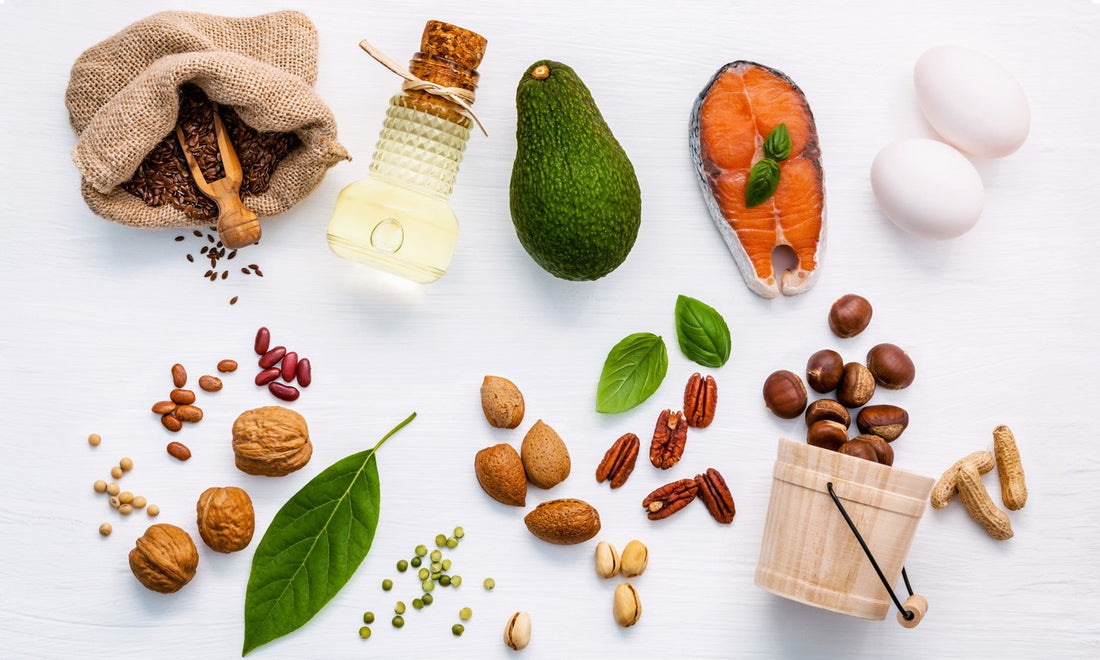 Healthy fats and protein sources: avocado, nuts, seeds, salmon, eggs on a white background.