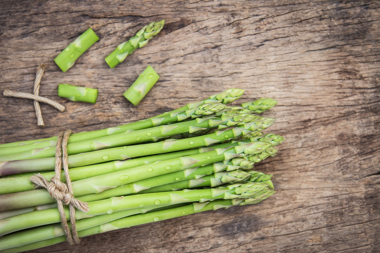 Fresh asparagus bundle on rustic wooden table.