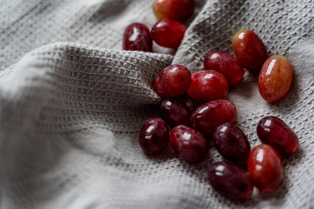 Red grapes on a textured grey cloth.