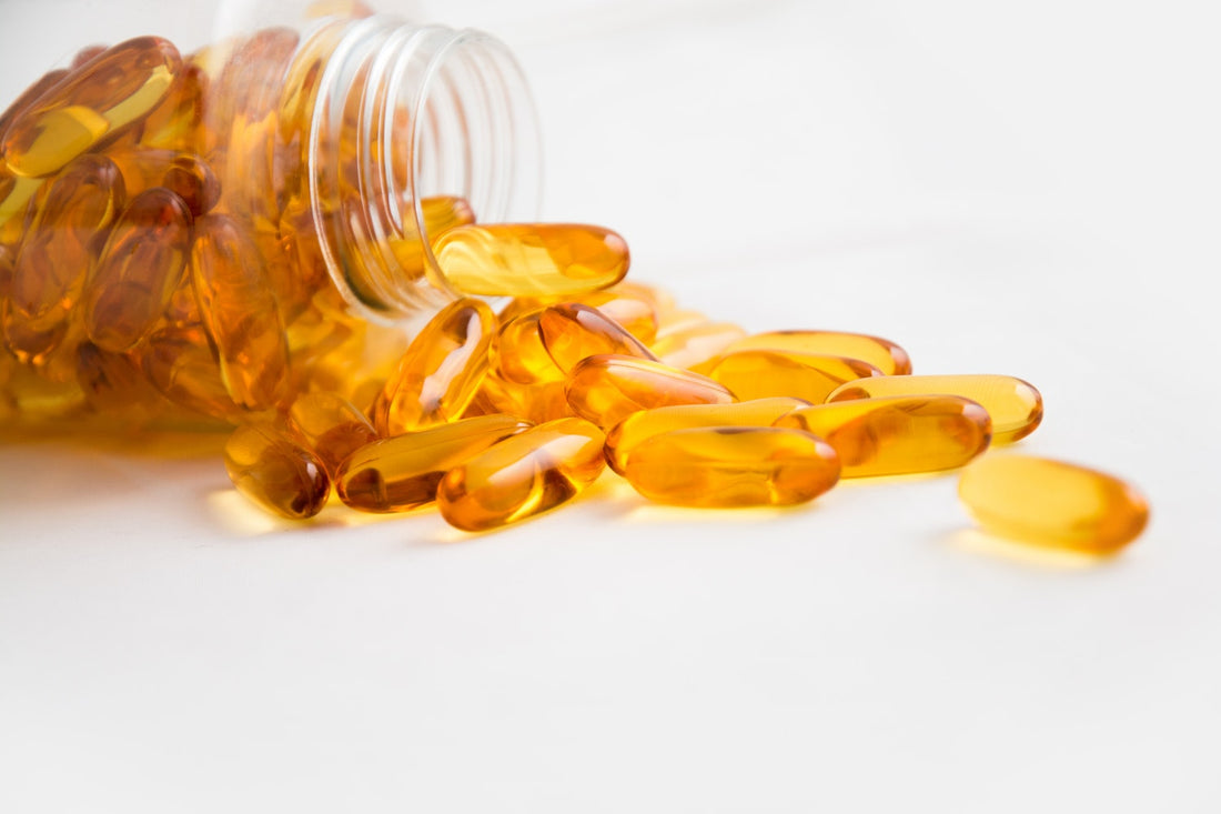 Spilled amber capsules from a glass bottle on a white surface.