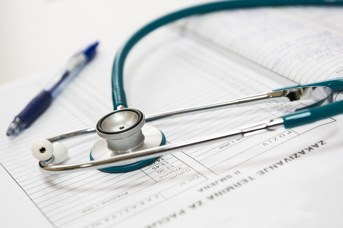 Stethoscope and pen on medical documents in a healthcare setting.