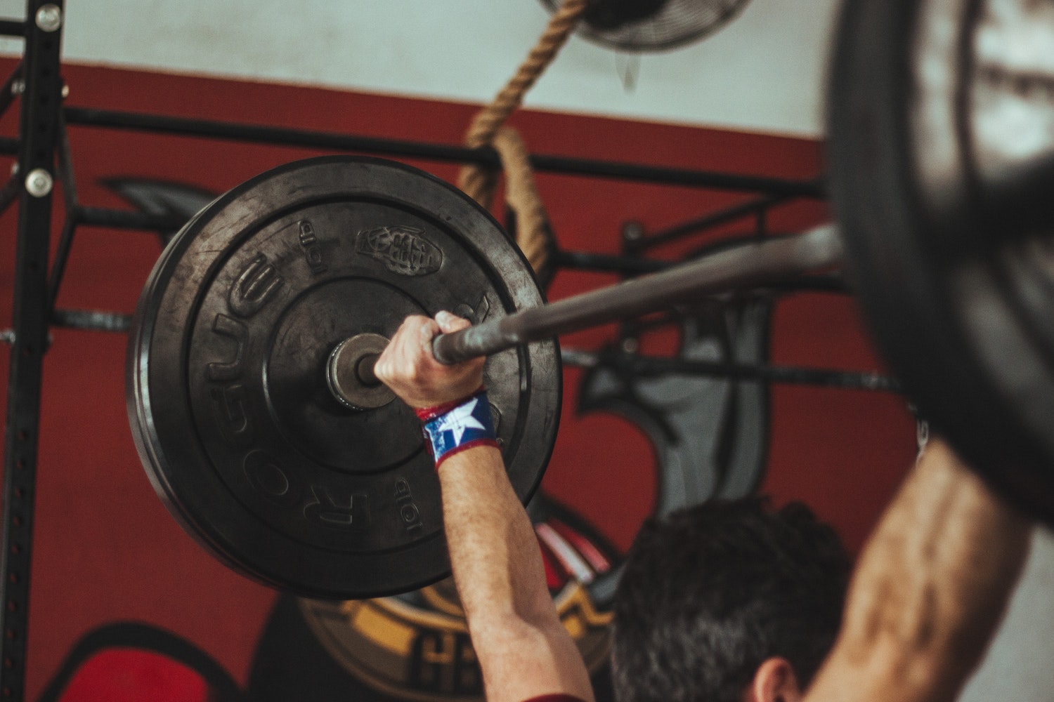 Person lifting barbell during workout, gym strength training