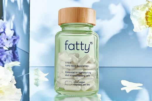 Fatty15's C15 supplement bottle with flowers on a reflective surface.