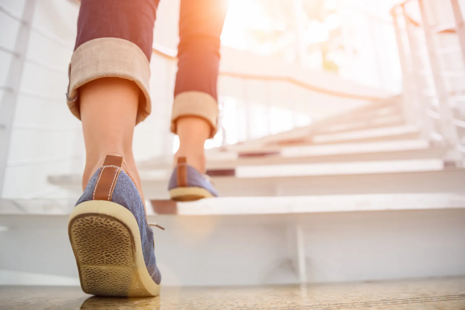 Person walking up sunlit stairs in casual shoes