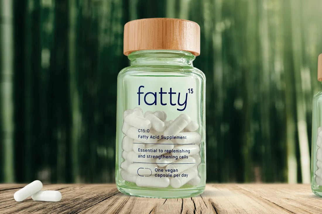 Fatty15's C15 supplement bottle on wooden table with bamboo background.