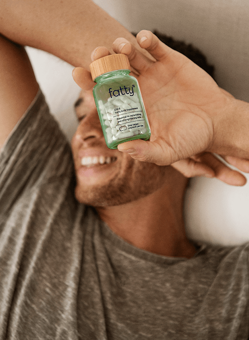 Man smiling and holding Fatty15's C15 supplement bottle.