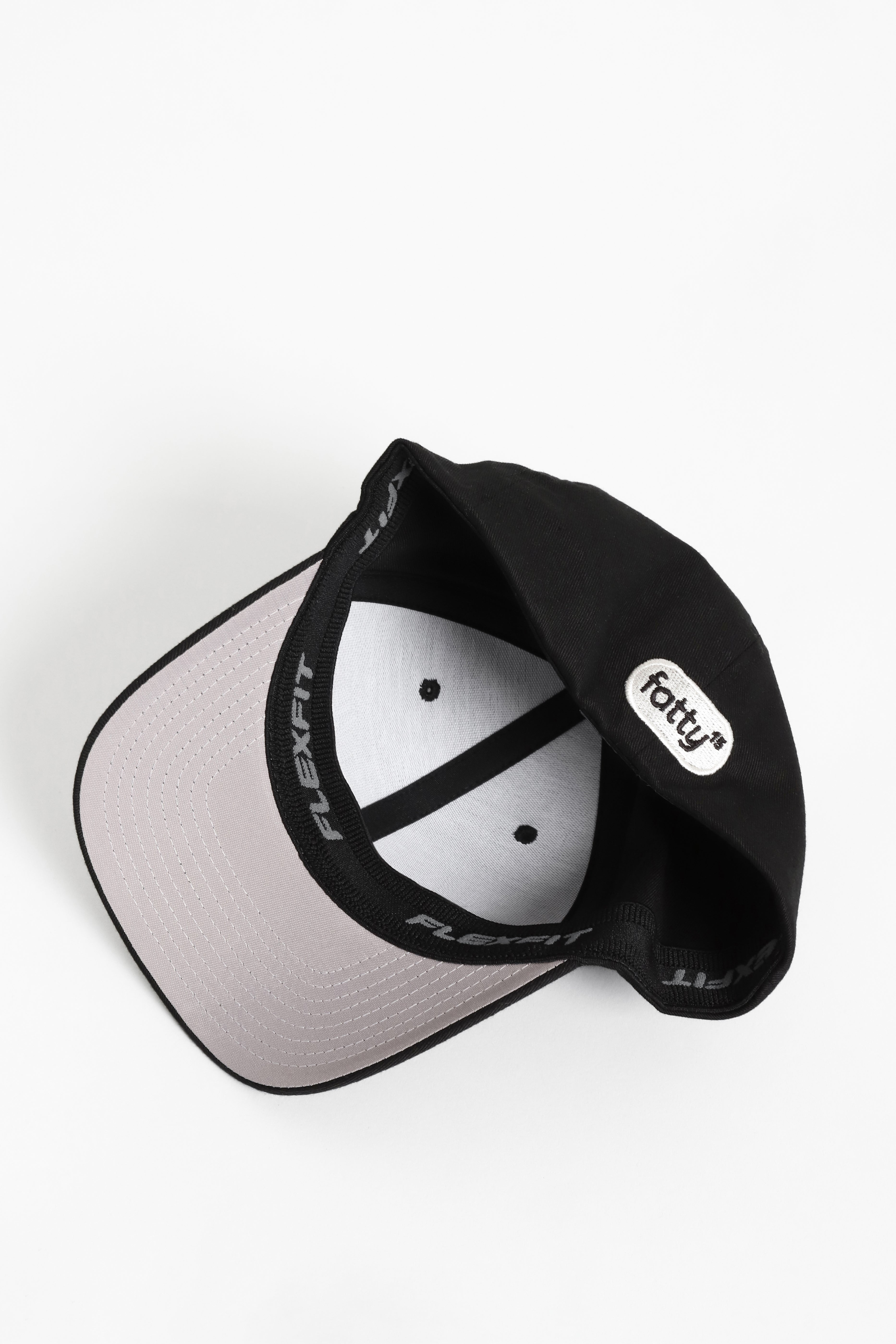 Black baseball cap with beige brim, top view.