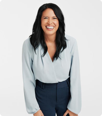 Dr. Stephanie Venn-Watson in a light blue blouse and dark pants, standing against a white background.