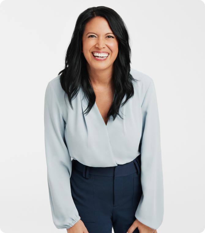 Dr. Stephanie Venn-Watson in a light blue blouse and dark pants, standing against a white background.