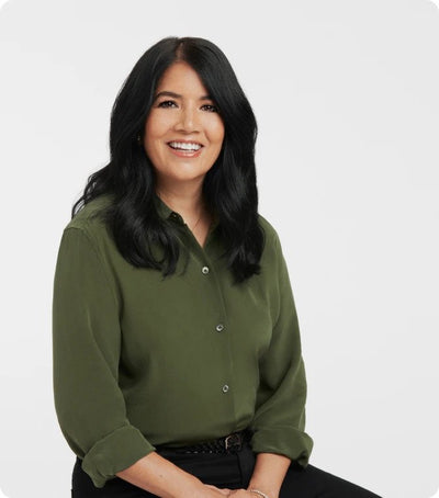 Smiling person in green shirt with dark hair, sitting against white background.