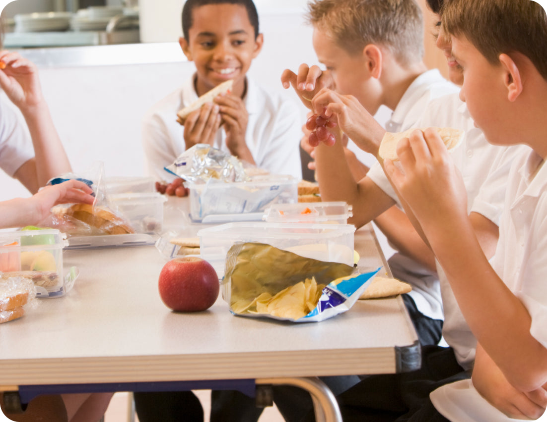 Children enjoying packed lunch at school table.